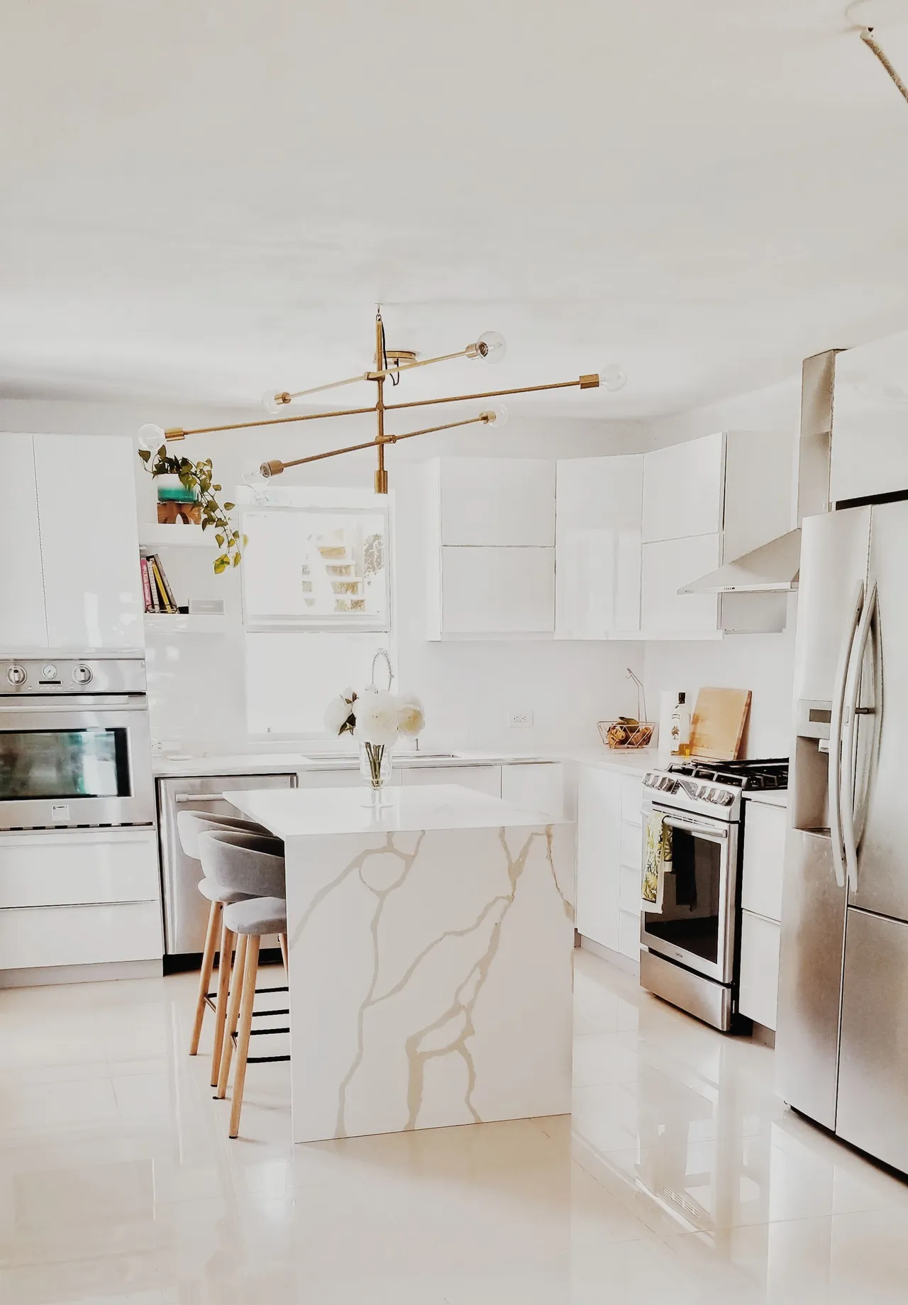 A sunlit kitchen with white cabinetry and a marble island